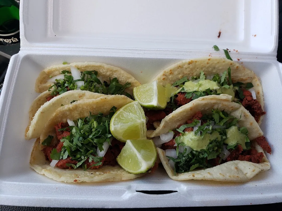 Tacos with red-seasoned meat, cilantro, onion and lime